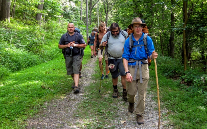 a group of veterans navigate a grassy trail on an outward bound expedition 